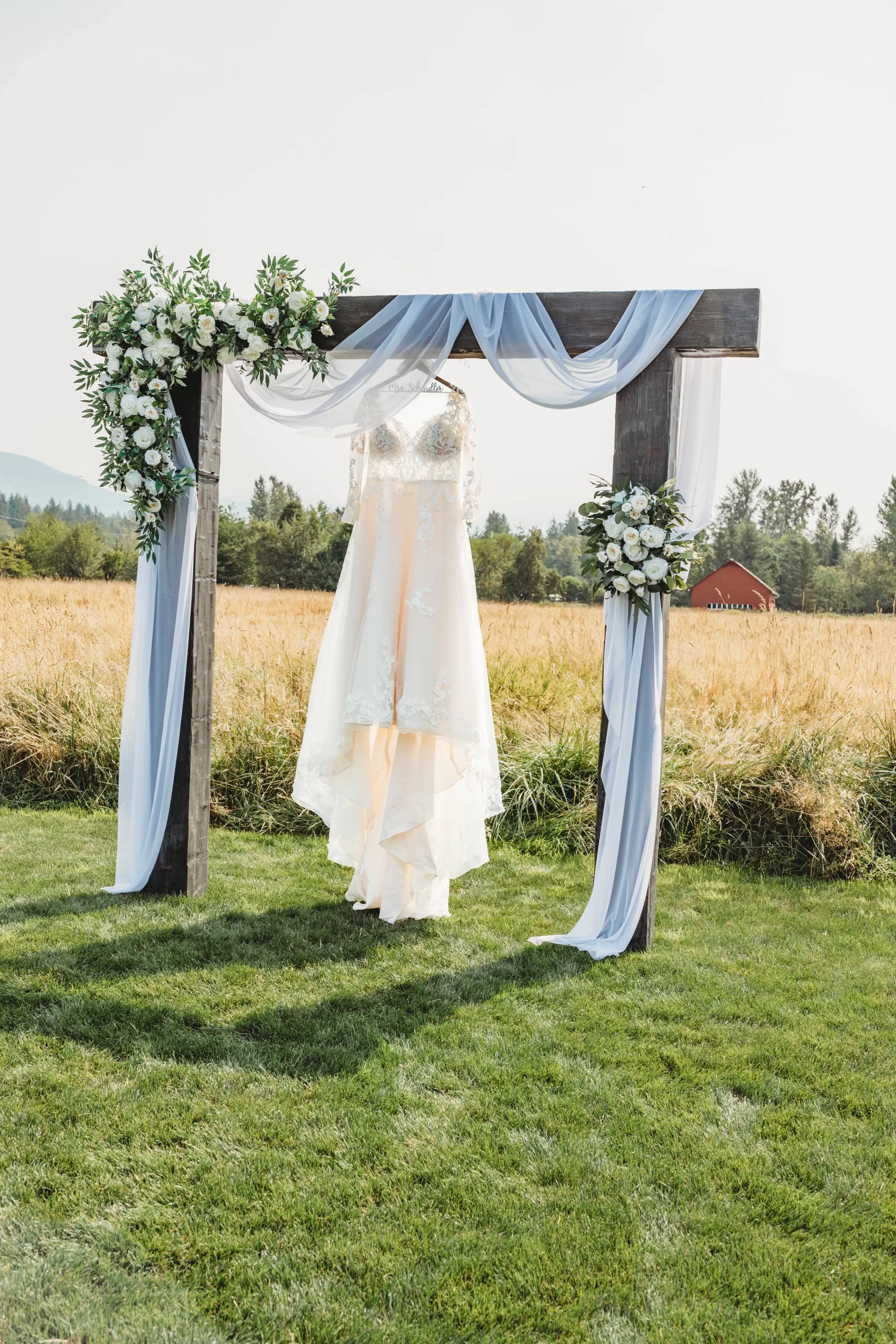Wedding dress hanging on wedding arbor at Mount Peak Farm in Enumclaw, WA. Photo by Essence of Us Photography