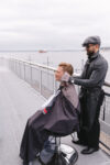 Barber preparing groom for wedding celebration with Puget Sound view in the background in Seattle
