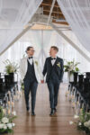 Grooms recessional after their wedding ceremony featuring elegant draping and bespoke floral arrangements at their luxury Architectural Romance wedding editorial at the Point at Pier 70 in Seattle