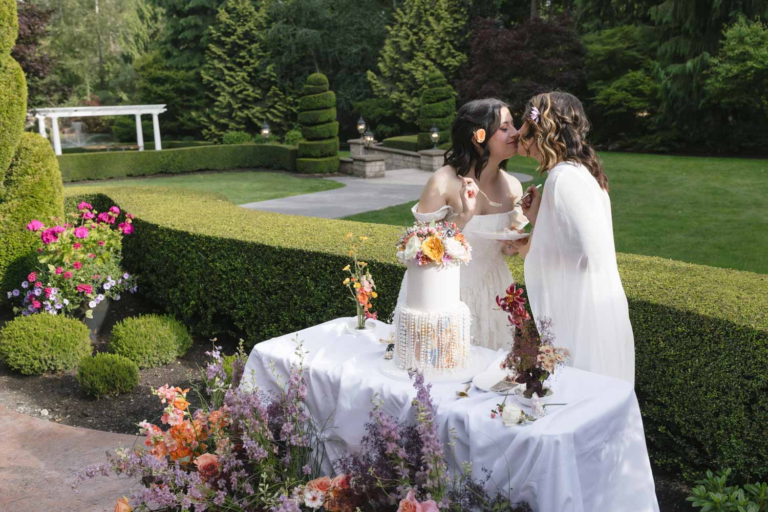 Brides share a kiss after feeding each other a bite of wedding cake