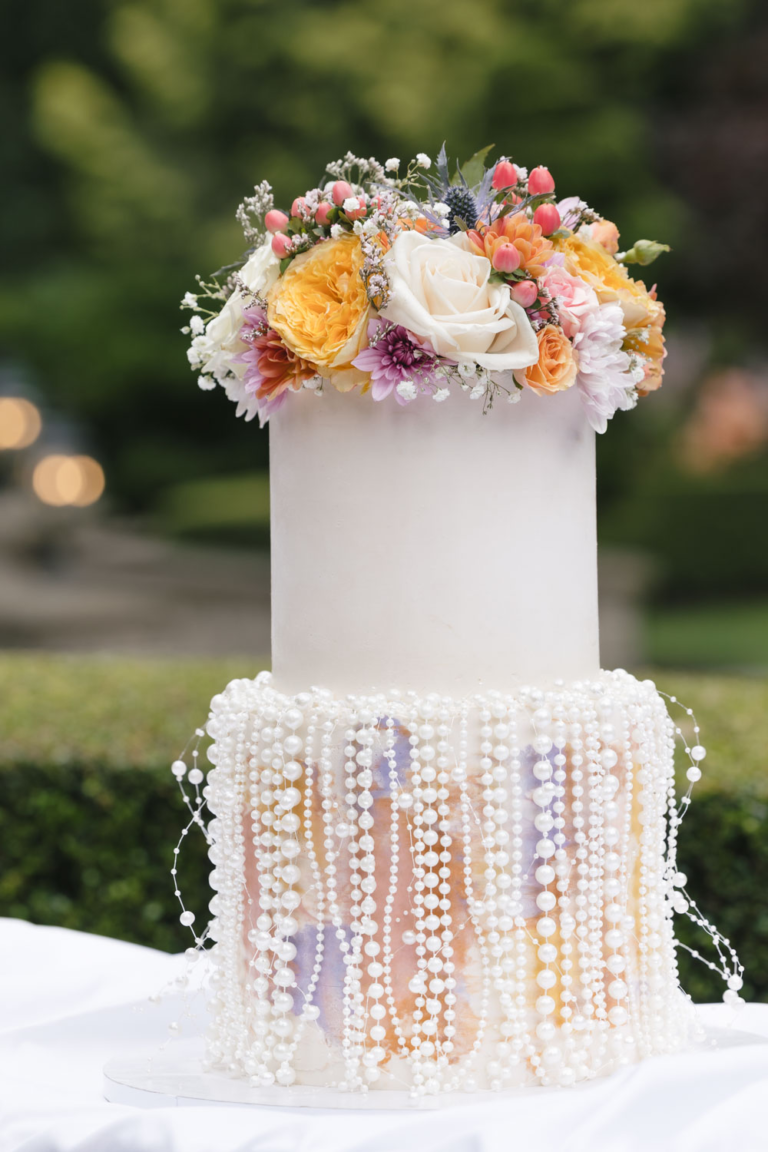 Two-tier wedding cake displayed on a white tablecloth at Rock Creek Gardens