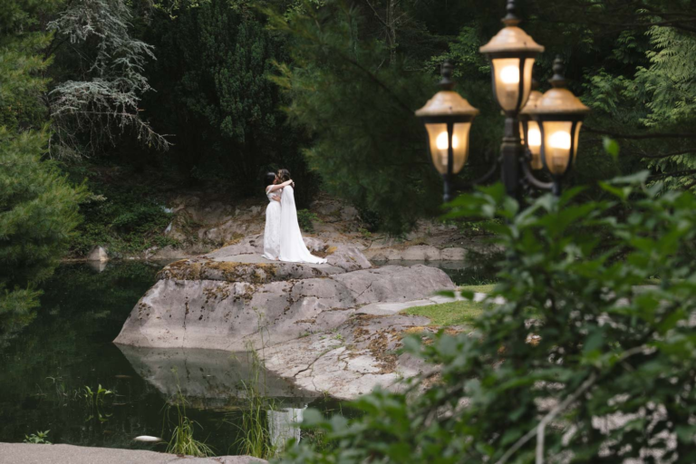 Brides embrace and share a private moment overlooking a large koi pond.