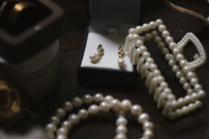 Bridal details including a set of earrings, a pearl hair clip, and pearl bracelets.