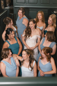 Bride and bridesmaids standing on stairwell at Hotel Scandi in Poulsbo, WA. Bride is winking while the bridesmaids are looking elsewhere and talking amongst themselves
